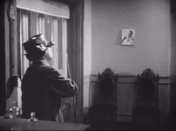 Movie still from “Diary of a Lost Girl” (1929), directed by Georg Wilhelm Pabst – A man standing in front of a window with a painting on the wall; Medium shot, Low angle