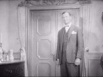 Movie still from “Diary of a Lost Girl” (1929), directed by Georg Wilhelm Pabst – A man standing in front of an open door; Medium shot, Low angle