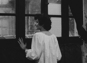 Movie still from “Diary of a Pregnant Woman” (1958), directed by Agnès Varda – A woman standing in front of an open window; Medium shot, High angle