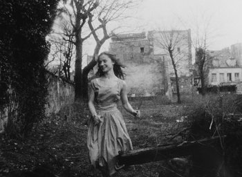 Movie still from “Diary of a Pregnant Woman” (1958), directed by Agnès Varda – An old photo of a woman running in a field; Medium shot, Low angle