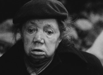 Movie still from “Diary of a Pregnant Woman” (1958), directed by Agnès Varda – An old woman wearing a hat and a jacket; Close Up shot, Low angle