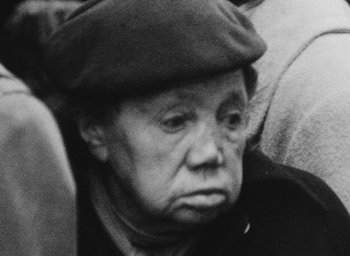 Movie still from “Diary of a Pregnant Woman” (1958), directed by Agnès Varda – An older woman wearing a hat and looking sad; Close Up shot, High angle