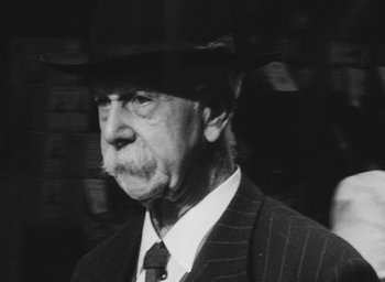 Movie still from “Diary of a Pregnant Woman” (1958), directed by Agnès Varda – An older man wearing a hat and a suit; Close Up shot, Low angle