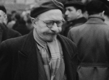 Movie still from “Diary of a Pregnant Woman” (1958), directed by Agnès Varda – An old man wearing glasses and a hat; Close Up shot, High angle