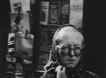 Movie still from “Diary of a Pregnant Woman” (1958), directed by Agnès Varda – An older woman wearing glasses is looking at the camera; Close Up shot, Over the shoulder angle