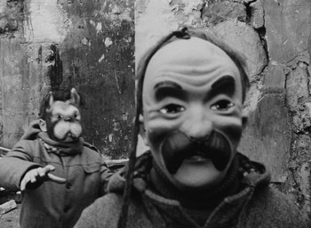 Movie still from “Diary of a Pregnant Woman” (1958), directed by Agnès Varda – A man with a mask on and a dog in the background; Close Up shot, Low angle