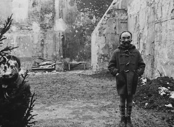 Movie still from “Diary of a Pregnant Woman” (1958), directed by Agnès Varda – A child wearing a gas mask stands in the dirt; Medium shot, Low angle