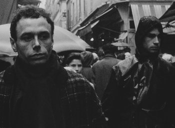 Movie still from “Diary of a Pregnant Woman” (1958), directed by Agnès Varda – A black and white photo of people walking down a city street; Close Up shot, Low angle