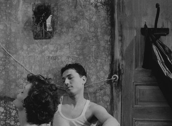 Movie still from “Diary of a Pregnant Woman” (1958), directed by Agnès Varda – A man and a woman are standing in front of a door; Medium shot, Overhead angle