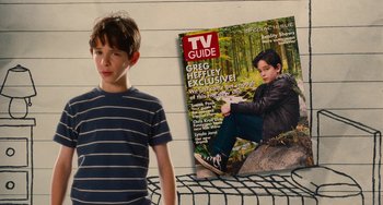 Movie still from “Diary of a Wimpy Kid” (2010), directed by Thor Freudenthal – A young boy standing next to a magazine cover; Medium shot, High angle