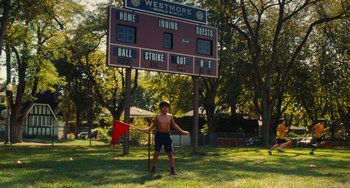 Movie still from “Diary of a Wimpy Kid” (2010), directed by Thor Freudenthal – A man standing in front of a baseball scoreboard; Wide shot, Low angle