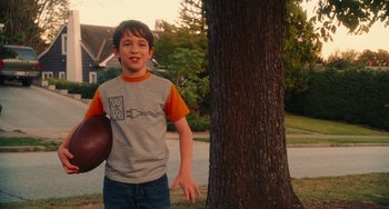 Movie still from “Diary of a Wimpy Kid” (2010), directed by Thor Freudenthal – A young boy holding a frisbee in front of a tree; Medium shot, Over the shoulder angle