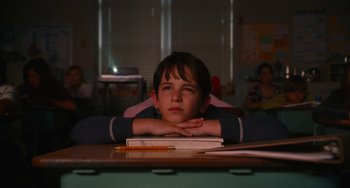 Movie still from “Diary of a Wimpy Kid” (2010), directed by Thor Freudenthal – A boy sitting at a desk with his head resting on a book; Medium shot, Low angle