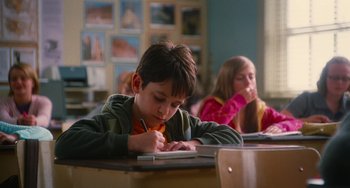 Movie still from “Diary of a Wimpy Kid” (2010), directed by Thor Freudenthal – A young boy writing on a notebook in a classroom; Medium shot, Low angle