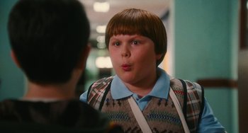 Movie still from “Diary of a Wimpy Kid” (2010), directed by Thor Freudenthal – A young boy making a funny face in front of another person; Medium shot, Over the shoulder angle