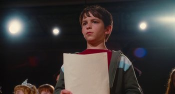 Movie still from “Diary of a Wimpy Kid” (2010), directed by Thor Freudenthal – A young boy holding a piece of paper in front of a crowd; Close Up shot, Low angle
