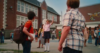 Movie still from “Diary of a Wimpy Kid” (2010), directed by Thor Freudenthal – A little girl in a school uniform waves to the crowd; Wide shot, Low angle