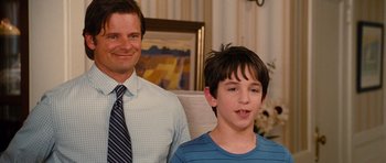 Movie still from “Diary of a Wimpy Kid: Rodrick Rules” (2011), directed by David Bowers – A man and a boy standing next to each other in a room; Medium shot, Over the shoulder angle