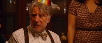 Movie still from “Diary of a Wimpy Kid: Rodrick Rules” (2011), directed by David Bowers – An older man wearing a bow tie and a party hat; Close Up shot, Over the shoulder angle