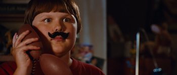 Movie still from “Diary of a Wimpy Kid: Rodrick Rules” (2011), directed by David Bowers – A young boy with a fake mustache on his face; Close Up shot, Over the shoulder angle