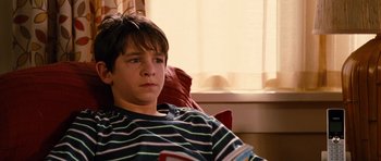 Movie still from “Diary of a Wimpy Kid: Rodrick Rules” (2011), directed by David Bowers – A young boy sitting in a chair reading a book; Close Up shot, High angle
