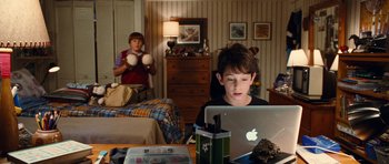Movie still from “Diary of a Wimpy Kid: Rodrick Rules” (2011), directed by David Bowers – A young boy sitting in front of an open laptop computer; Medium shot, High angle