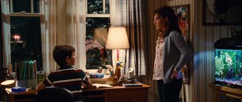 Movie still from “Diary of a Wimpy Kid: Rodrick Rules” (2011), directed by David Bowers – A woman standing next to a boy in a room; Medium shot, Over the shoulder angle