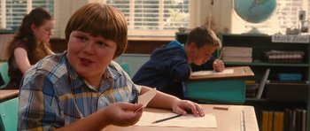 Movie still from “Diary of a Wimpy Kid: Rodrick Rules” (2011), directed by David Bowers – Two young boys sitting at a table in front of papers and pencils; Medium shot, Over the shoulder angle