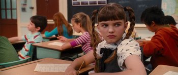 Movie still from “Diary of a Wimpy Kid: Rodrick Rules” (2011), directed by David Bowers – A little girl sitting at a desk in front of a chalkboard; Close Up shot, Over the shoulder angle