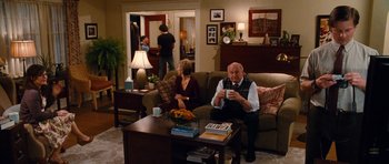 Movie still from “Diary of a Wimpy Kid: Rodrick Rules” (2011), directed by David Bowers – An older man sitting on a couch in a living room; Wide shot, Over the shoulder angle