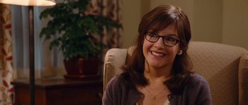 Movie still from “Diary of a Wimpy Kid: Rodrick Rules” (2011), directed by David Bowers – A woman sitting in a chair wearing glasses and smiling; Close Up shot, Over the shoulder angle
