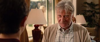 Movie still from “Diary of a Wimpy Kid: Rodrick Rules” (2011), directed by David Bowers – An older man sitting in front of a table lamp; Close Up shot, Over the shoulder angle