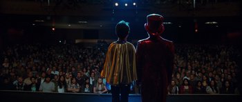 Movie still from “Diary of a Wimpy Kid: Rodrick Rules” (2011), directed by David Bowers – A man and a boy dressed as superheroes in front of an audience; Wide shot, High angle