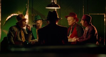 Movie still from “Dick Tracy” (1990), directed by Warren Beatty – A group of men sitting at a table with hats on; Medium shot, Over the shoulder angle