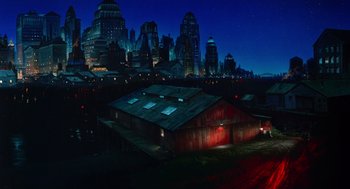 Movie still from “Dick Tracy” (1990), directed by Warren Beatty – A night view of a large city with buildings lit up in the dark; Extreme Wide shot, High angle