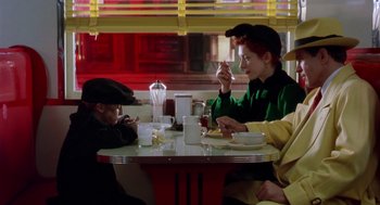 Movie still from “Dick Tracy” (1990), directed by Warren Beatty – A woman sitting at a table with a young child; Medium shot, Over the shoulder angle