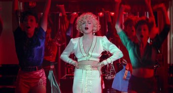 Movie still from “Dick Tracy” (1990), directed by Warren Beatty – A woman in a white dress is singing in front of a group of people; Medium shot, Low angle