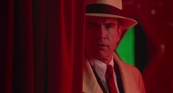 Movie still from “Dick Tracy” (1990), directed by Warren Beatty – A man wearing a suit and a hat standing in front of a red drape; Close Up shot, Low angle