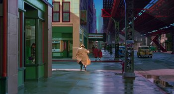 Movie still from “Dick Tracy” (1990), directed by Warren Beatty – A woman walking down the street wearing a long coat; Extreme Wide shot, High angle