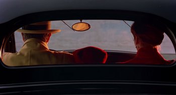 Movie still from “Dick Tracy” (1990), directed by Warren Beatty – A man and a woman in the back seat of a car; Wide shot, Over the shoulder angle