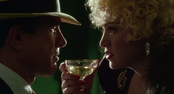 Movie still from “Dick Tracy” (1990), directed by Warren Beatty – A man and a woman holding a glass of wine; Close Up shot, Low angle
