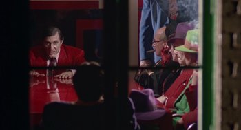 Movie still from “Dick Tracy” (1990), directed by Warren Beatty – A group of people sitting around a table; Medium shot, Over the shoulder angle