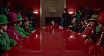 Movie still from “Dick Tracy” (1990), directed by Warren Beatty – A group of people sitting around a table in front of a fireplace; Wide shot, High angle