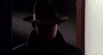 Movie still from “Dick Tracy” (1990), directed by Warren Beatty – A man wearing a hat and a black coat; Close Up shot, Low angle