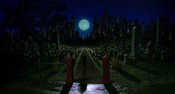 Movie still from “Dick Tracy” (1990), directed by Warren Beatty – A man standing in front of a cemetery at night with a full moon in the background; Extreme Wide shot, High angle