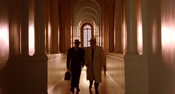 Movie still from “Dick Tracy” (1990), directed by Warren Beatty – A couple of men walking down a long hallway together; Wide shot, Low angle