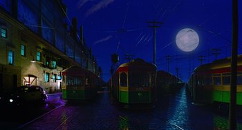 Movie still from “Dick Tracy” (1990), directed by Warren Beatty – Two trolleys are parked on the side of the road; Extreme Wide shot, Low angle