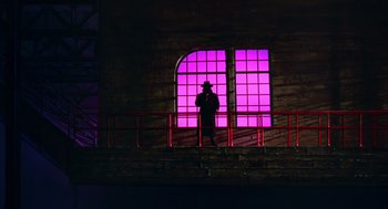 Movie still from “Dick Tracy” (1990), directed by Warren Beatty – A man standing in front of a window at night; Extreme Wide shot, Low angle