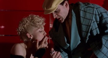 Movie still from “Dick Tracy” (1990), directed by Warren Beatty – A man and a woman are smoking a cigarette together; Close Up shot, Low angle