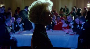 Movie still from “Dick Tracy” (1990), directed by Warren Beatty – A woman in a black dress standing in front of a crowd; Medium shot, Over the shoulder angle
